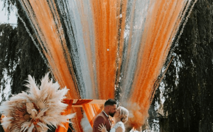 Mariés sous feux d'artifice de jour orange et blanc pour cérémonie laïque en extérieur, Hauts-de-France. Effets spéciaux mariage innovants par S'TORM EVENTS.