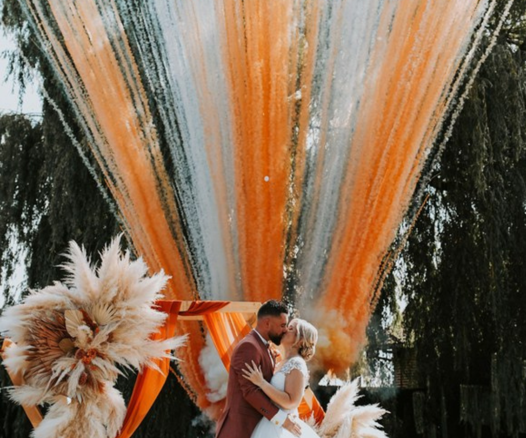 Mariés sous feux d'artifice de jour orange et blanc pour cérémonie laïque en extérieur, Hauts-de-France. Effets spéciaux mariage innovants par S'TORM EVENTS.
